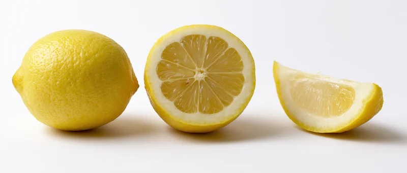 Three lemons whole sliced and wedged on white background