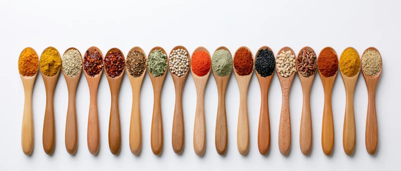 Wooden spoons each holding a different spice arranged in a horizontal row on a white background