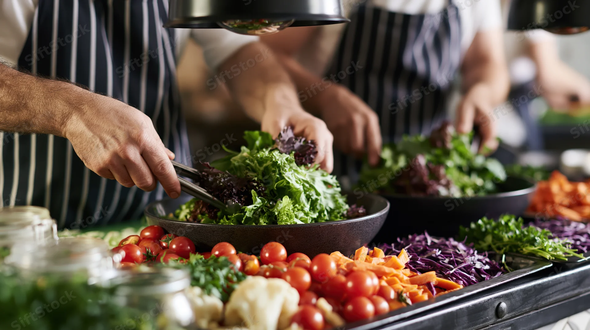 Chefs preparing fresh salad with vegetables and greens in a restaurant kitchen