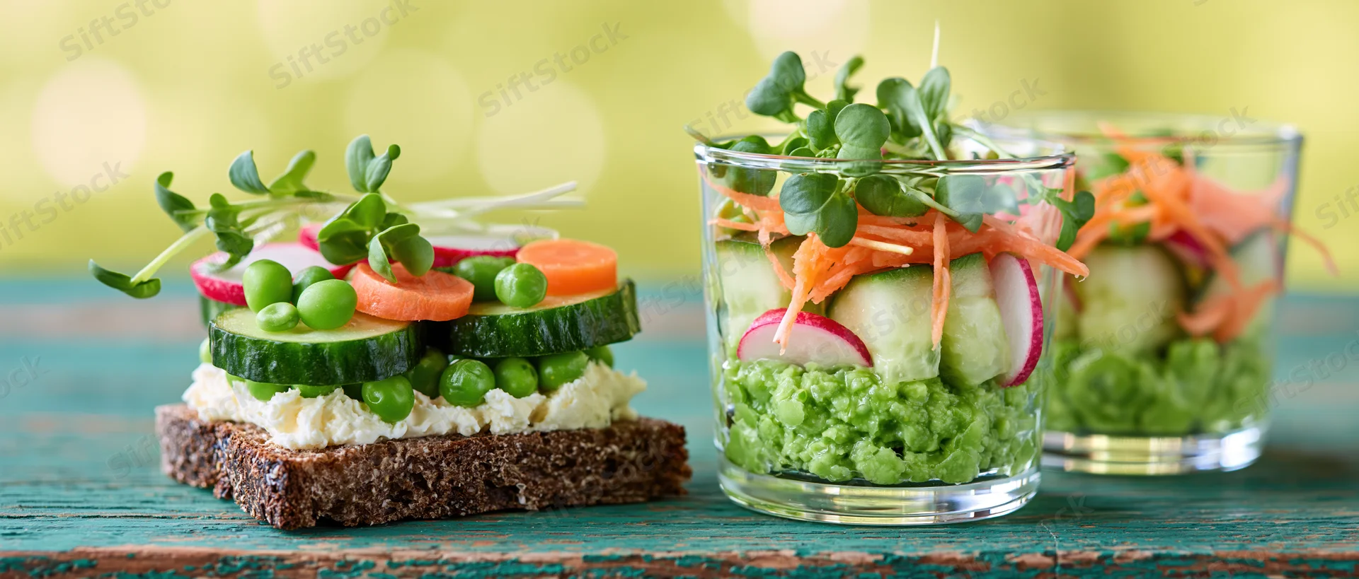 Two spring vegetable arrangements on rye crispbread and in glass jars on a wooden table