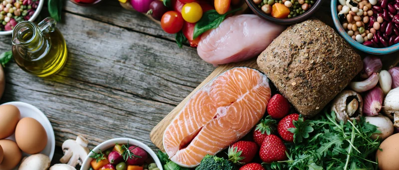 Salmon fillet and whole foods arranged on a weathered wooden table in a flat lay composition