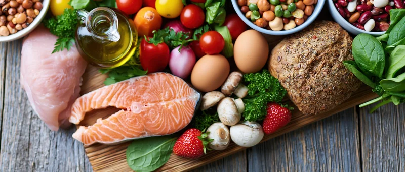 Salmon fillet and assorted whole foods arranged on a wooden board