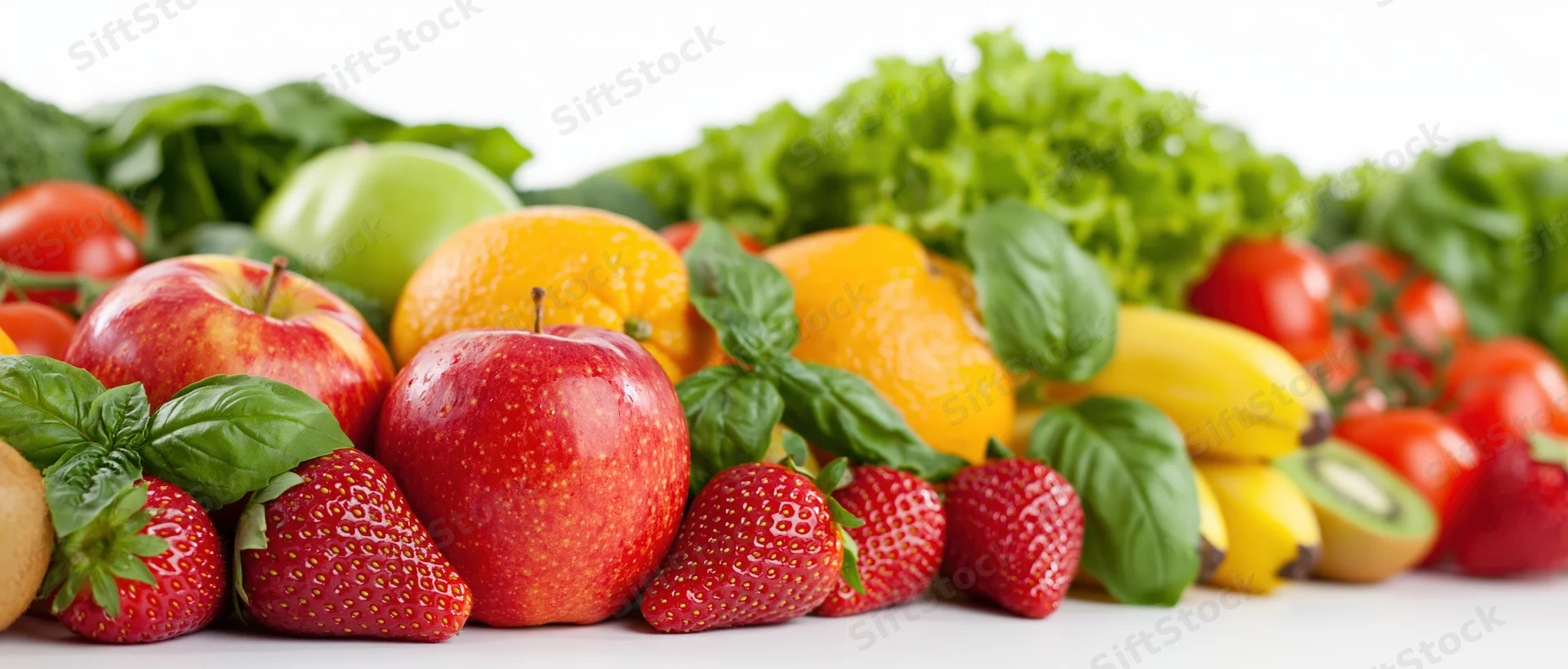 Fresh fruits and vegetables arranged in a wide horizontal row on a white surface