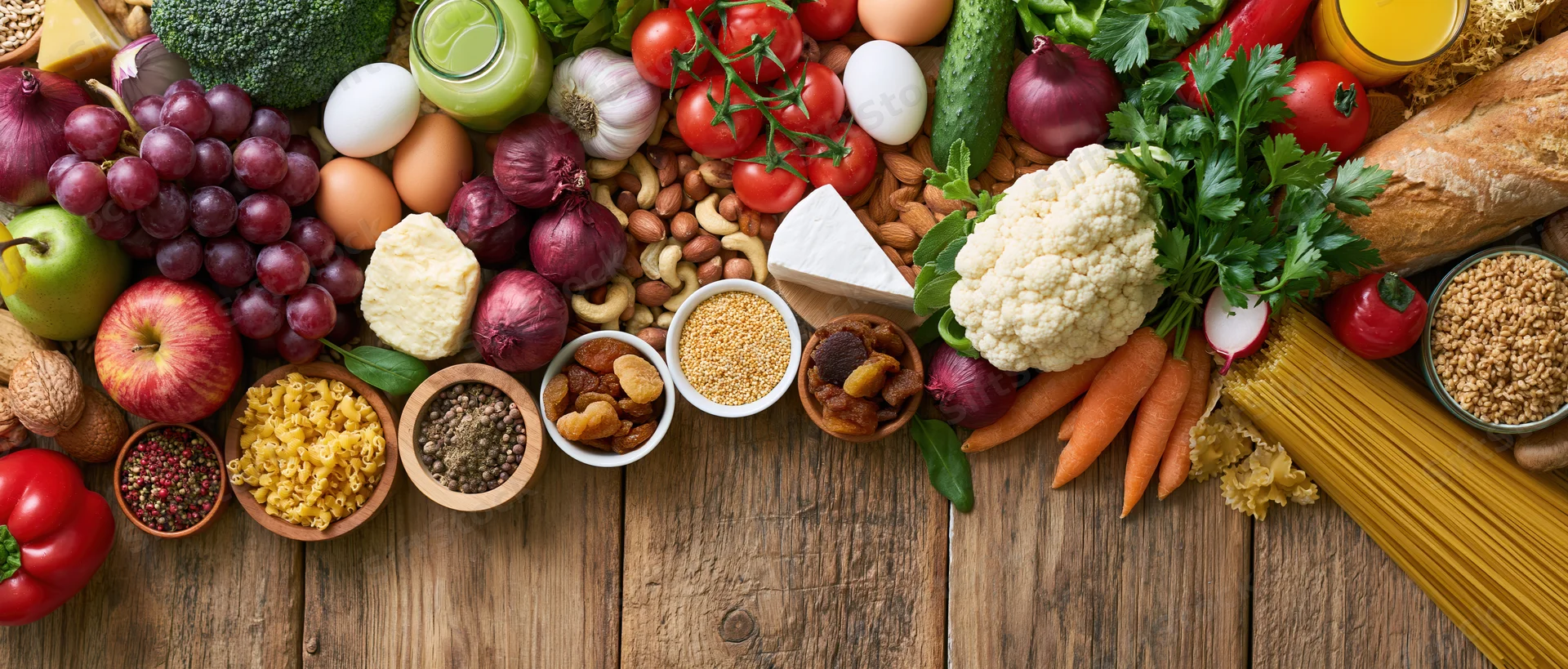 Variety of fresh whole foods arranged on wooden table in flat lay overhead view
