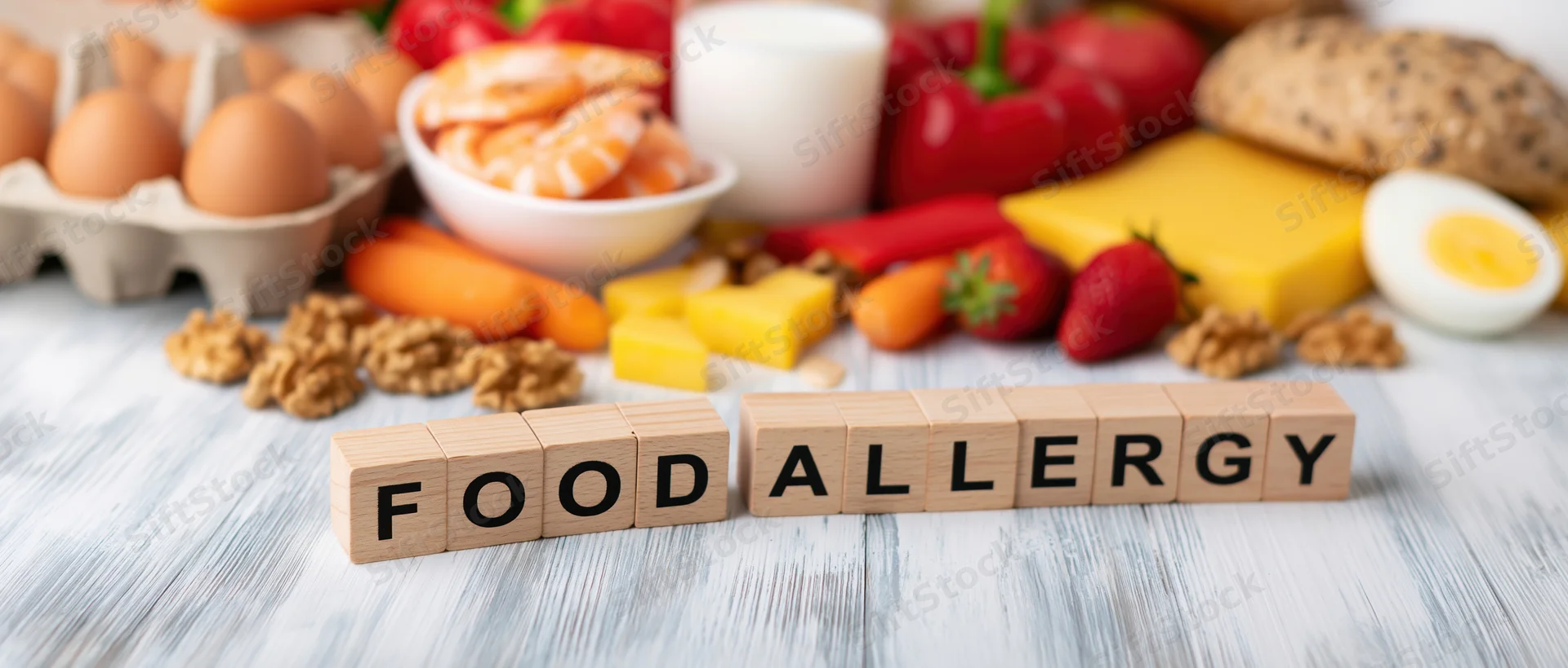 Wooden blocks spelling food allergy arranged on a table with various foods in background