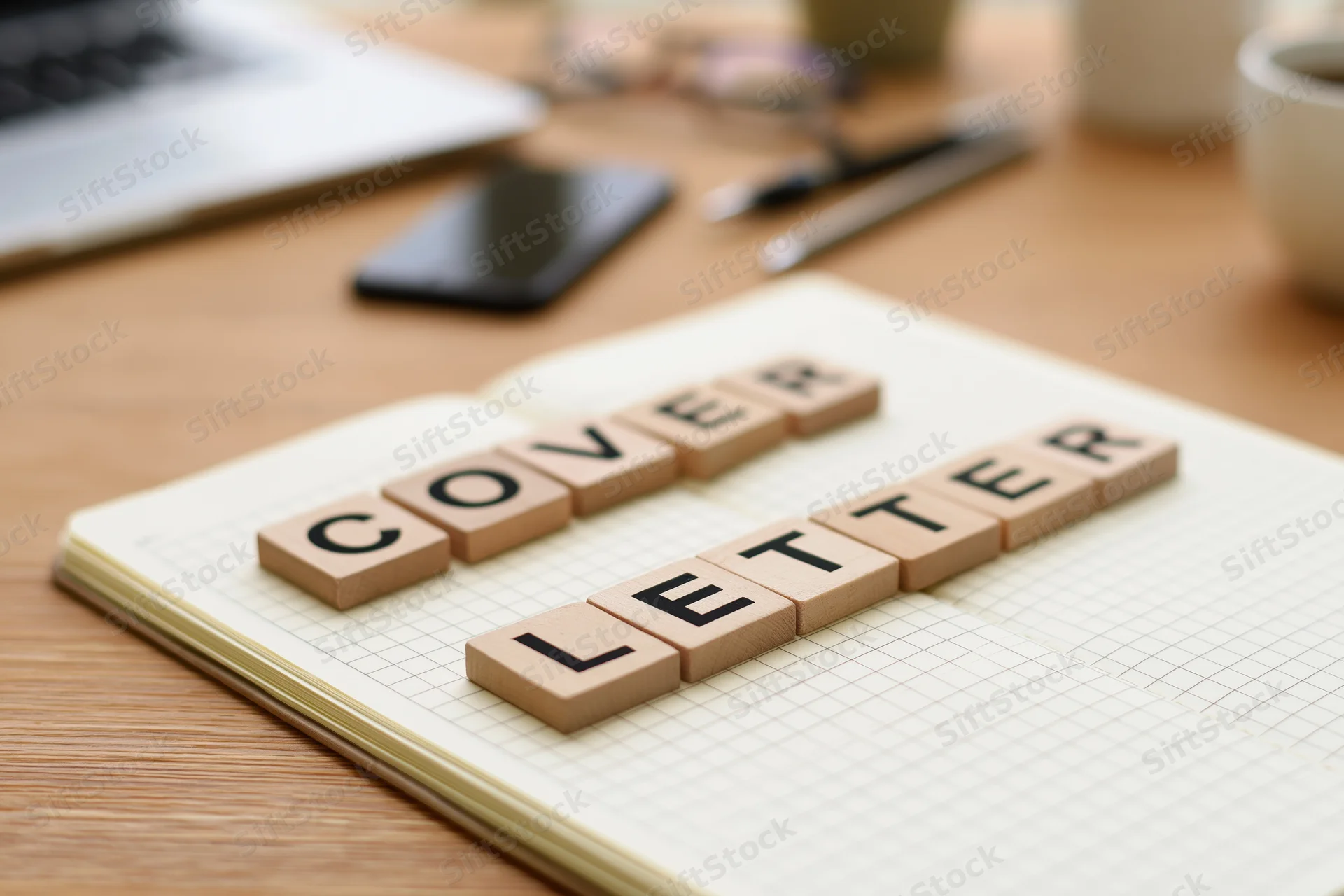 Wooden letter tiles spelling cover letter on open notebook grid paper on desk