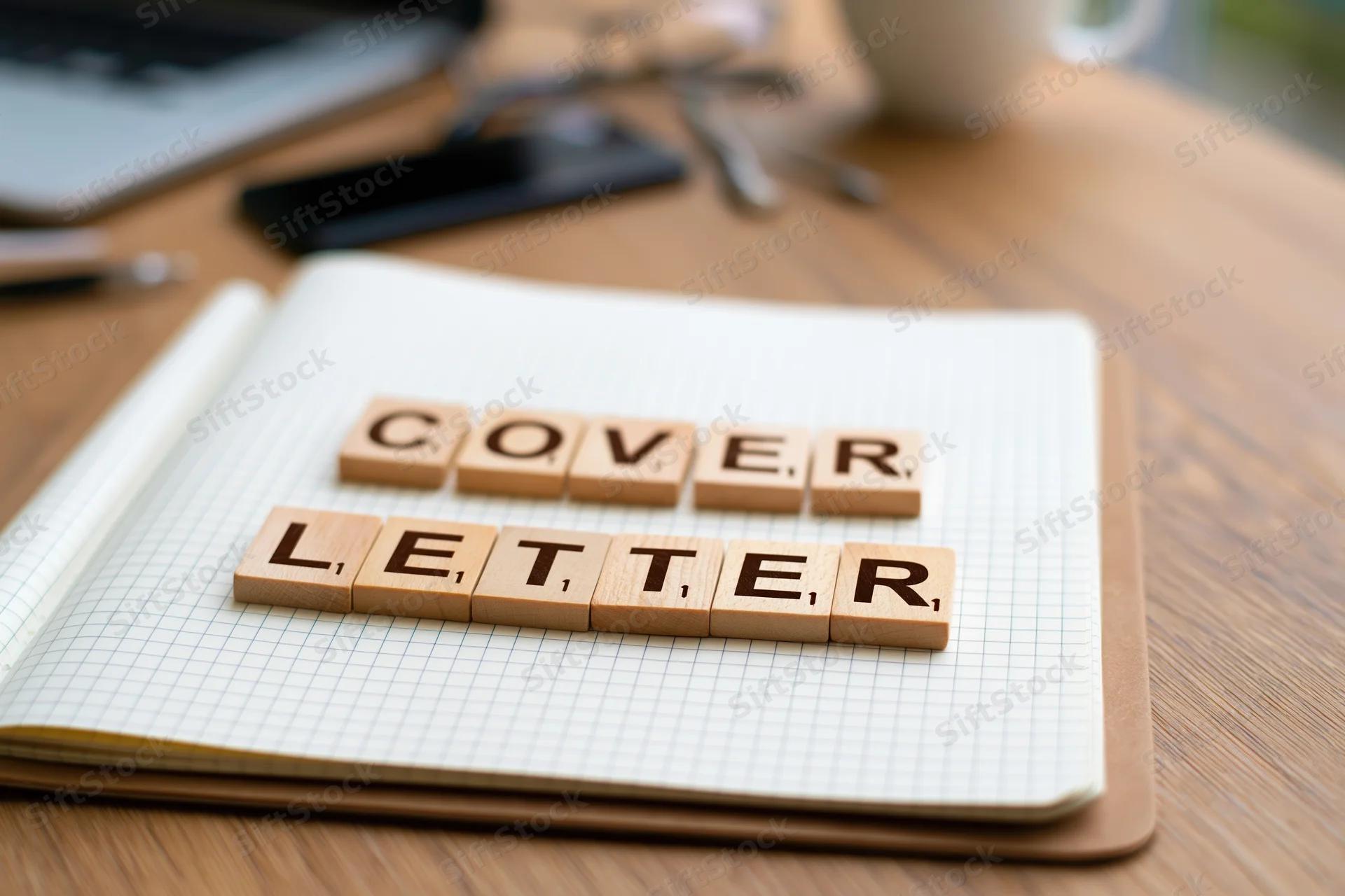 Wooden letter tiles spelling cover letter on an open notebook on a desk
