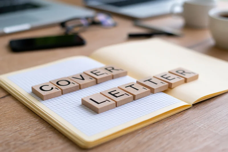 Wooden letter tiles spelling cover letter on open notebook grid paper on desk