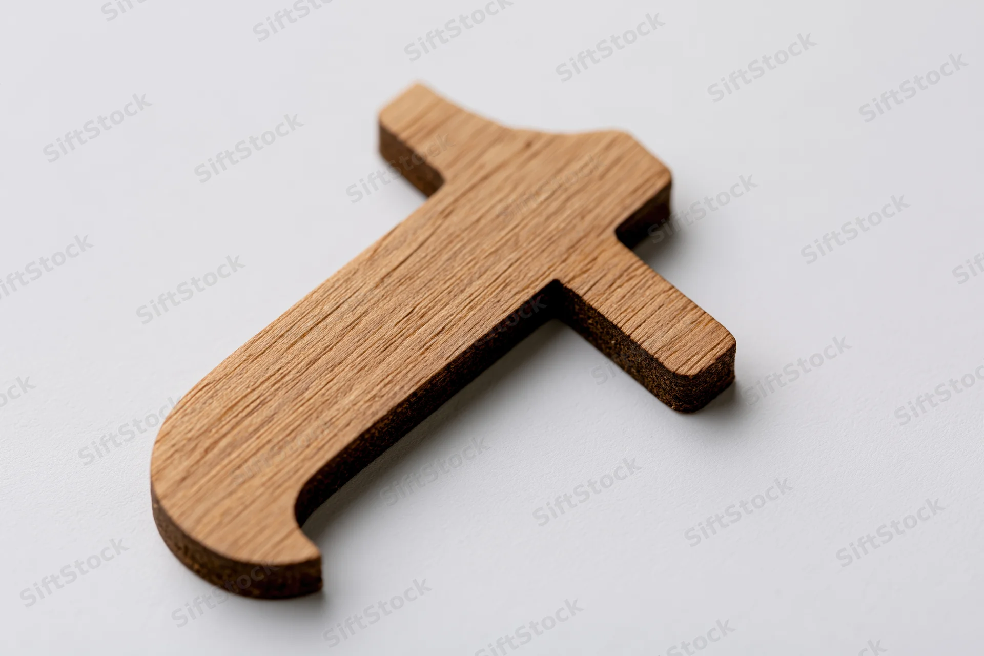 Wooden lowercase letter t cutout lying flat on a white surface