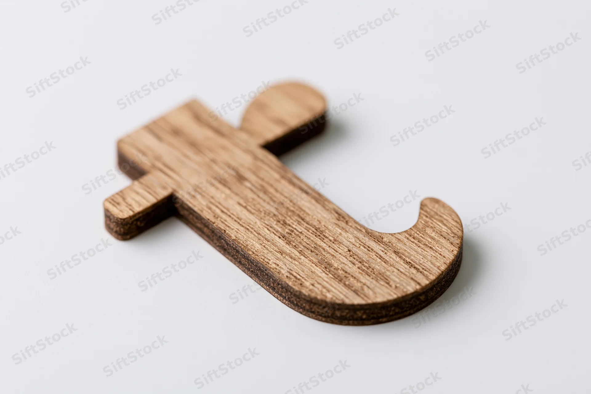 Wooden lowercase letter t cutout lying flat on a clean white background