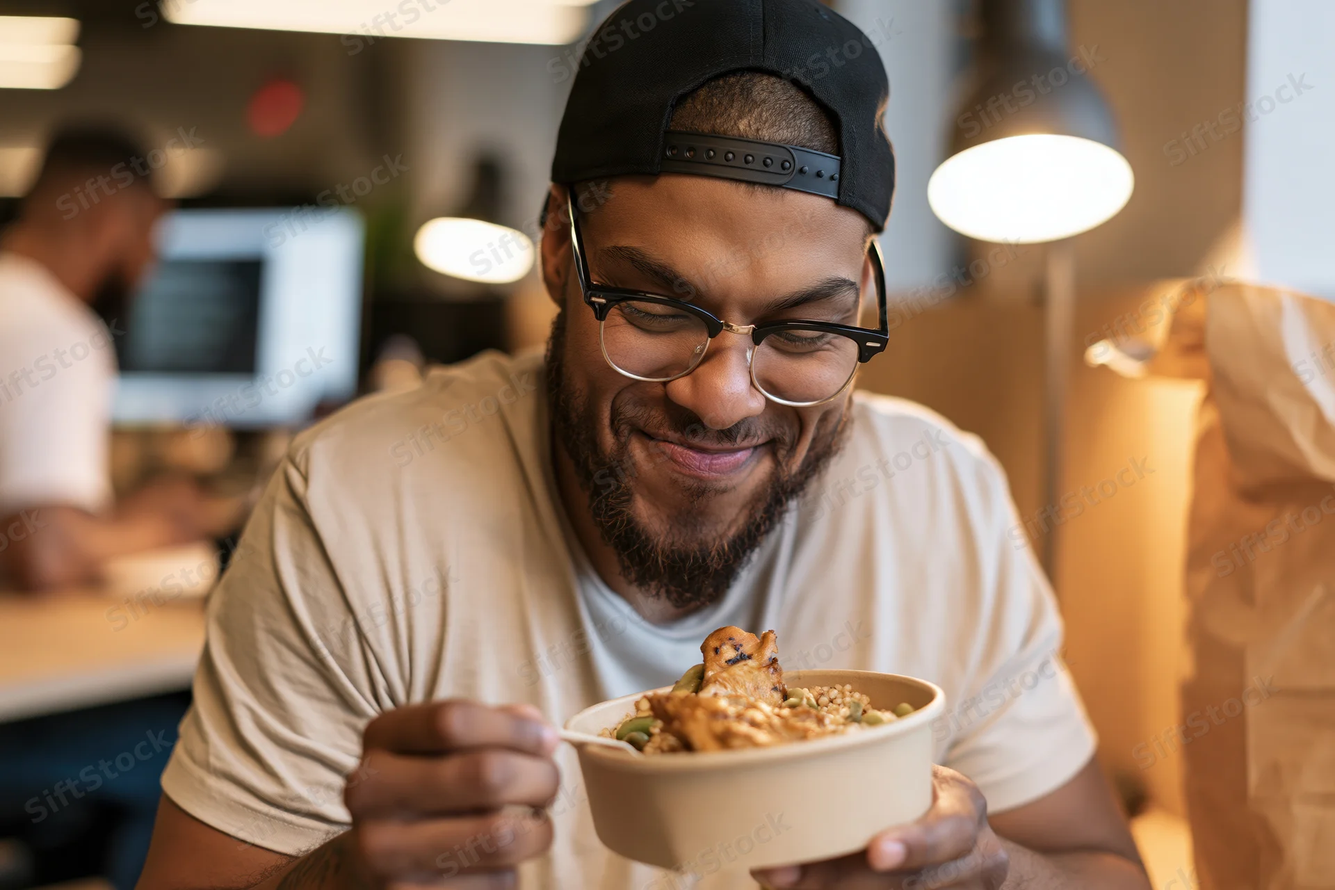 Man eating takeout meal from a bowl in an office setting