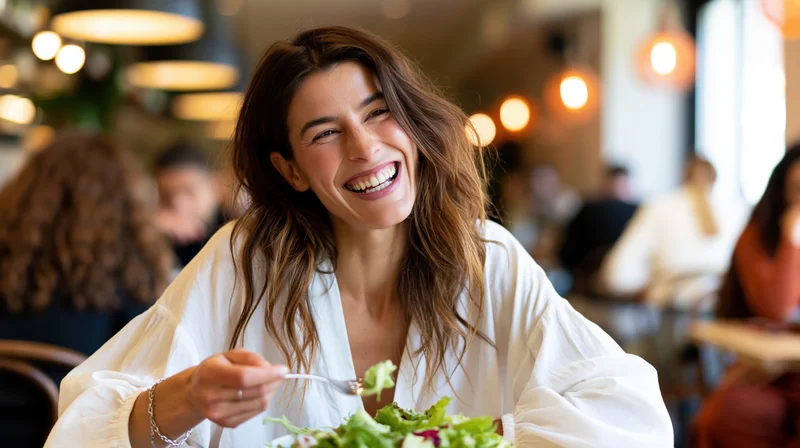Woman laughing while eating salad in a restaurant