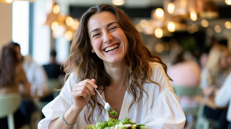 Woman laughing while eating salad in a restaurant