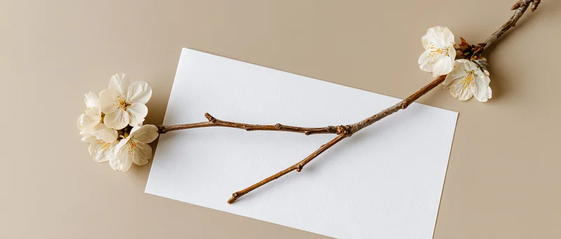Cherry blossom branch resting diagonally on white textured paper with copyspace on beige background