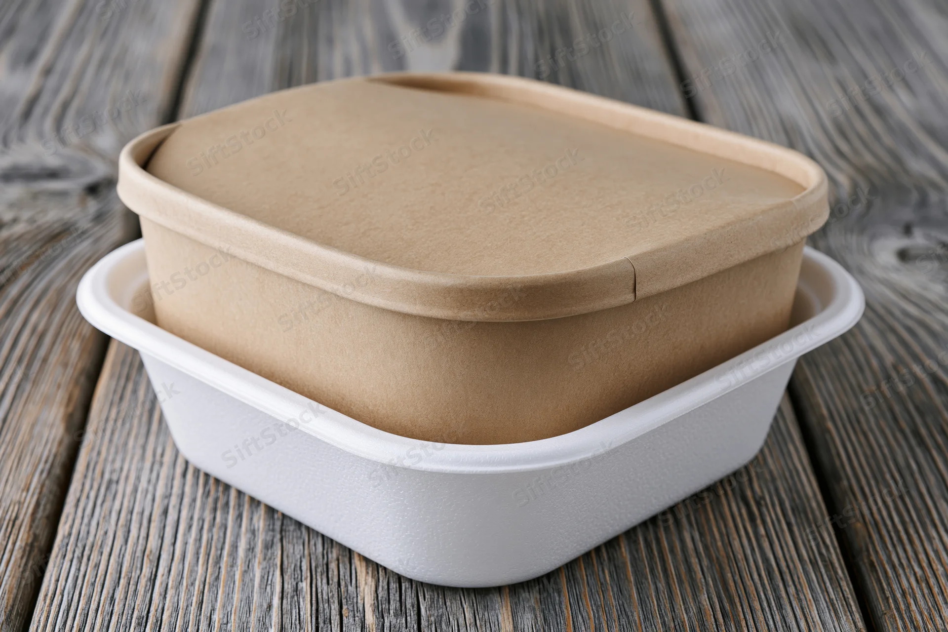 Kraft cardboard sleeve over white foam food container on wooden surface