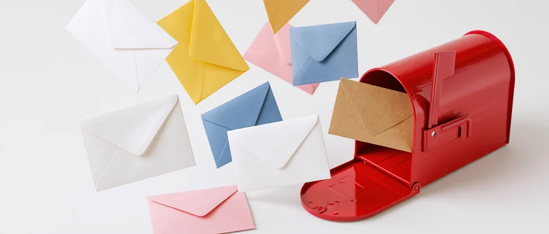 Red mailbox with open door and colorful envelopes floating around it on white background