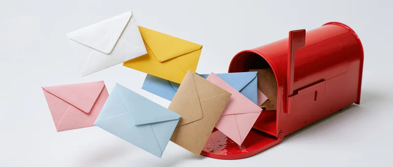 Red mailbox with open door and colorful envelopes spilling out on white background