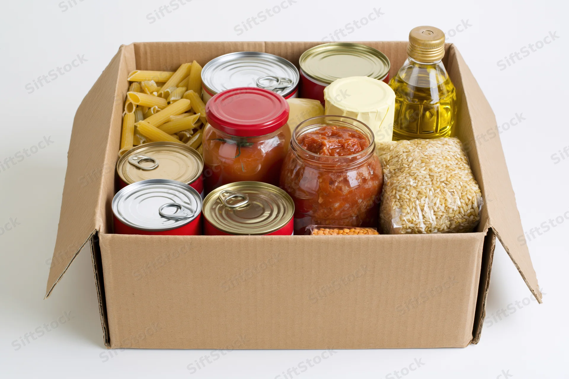 Open cardboard box filled with assorted nonperishable food items including canned goods, pasta, rice, and oil