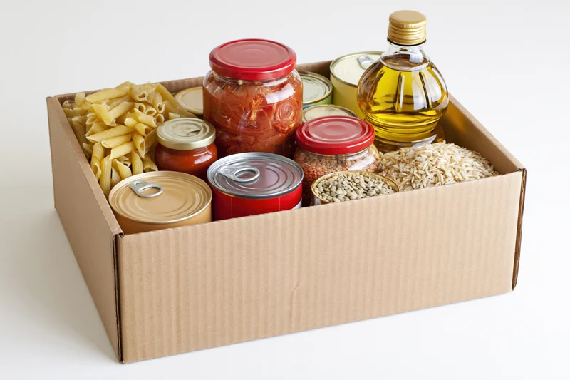 Cardboard box filled with assorted nonperishable food items on white background