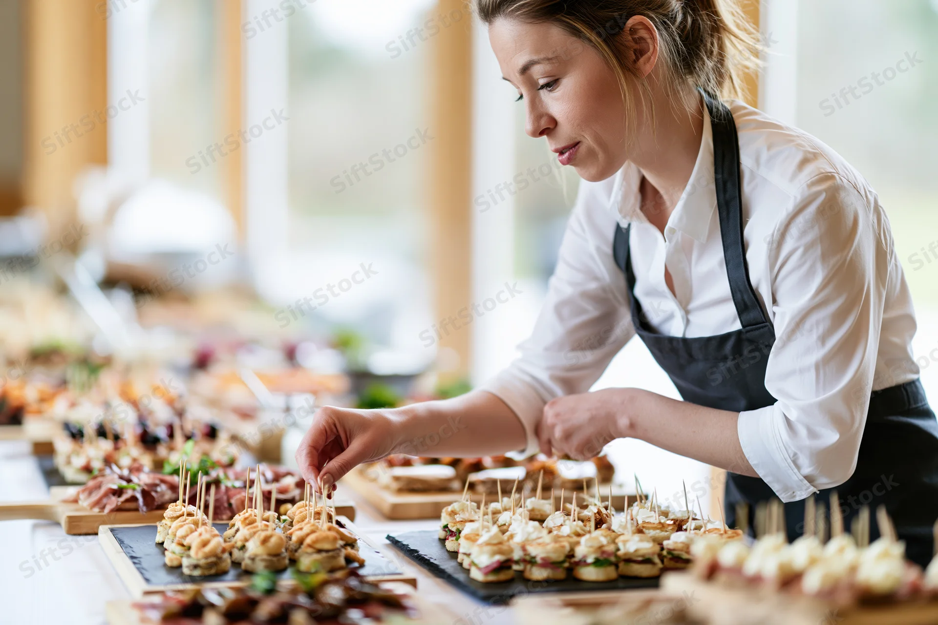 Woman arranging canapes on a buffet table for an event