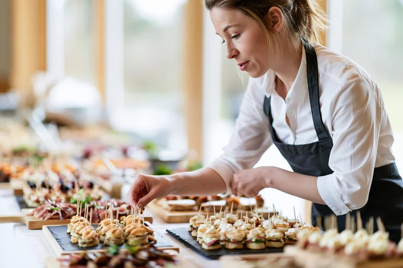 Woman arranging canapes on a buffet table for an event