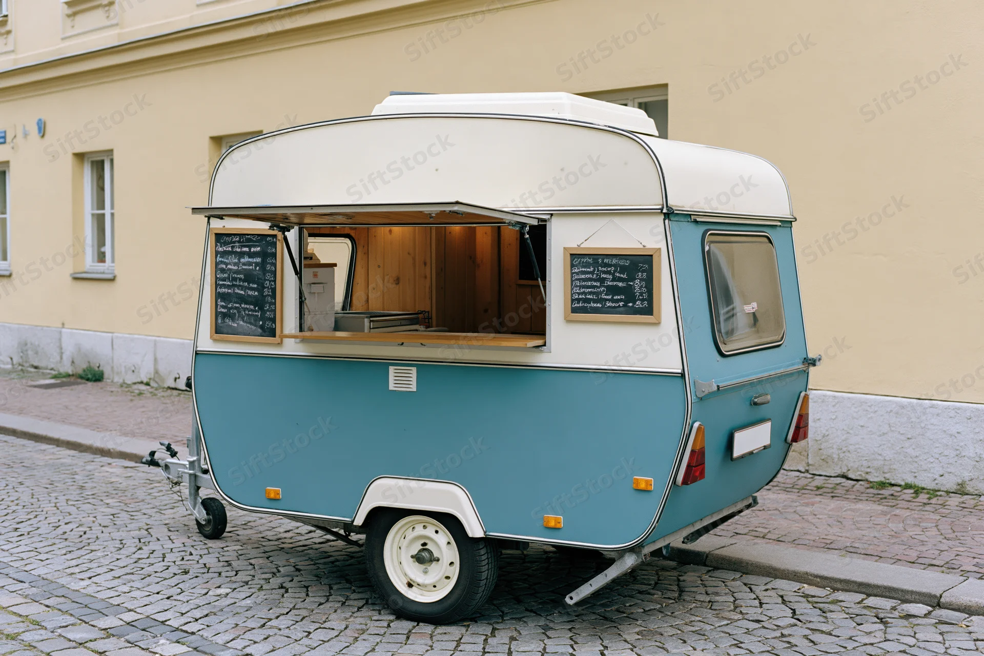 Vintage teal and white food trailer with open service window parked on cobblestone street