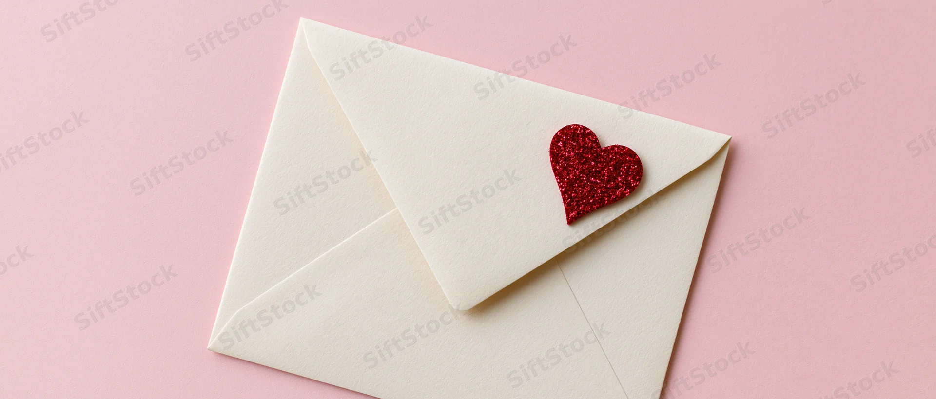 Cream envelope with red glitter heart seal on pink background