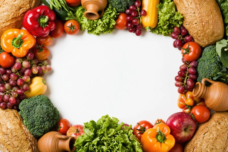 Fresh fruits and vegetables arranged in a border frame around a white center