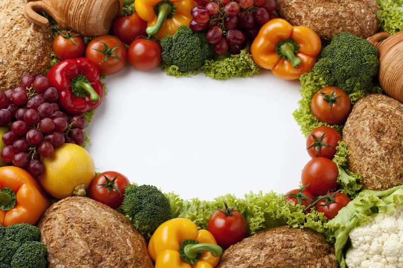 Fresh vegetables and fruits arranged in a circular border frame with copyspace in center