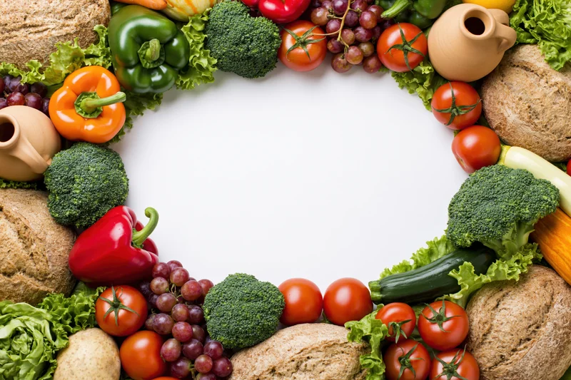 Fresh vegetables and fruits arranged in a circular border around a white center