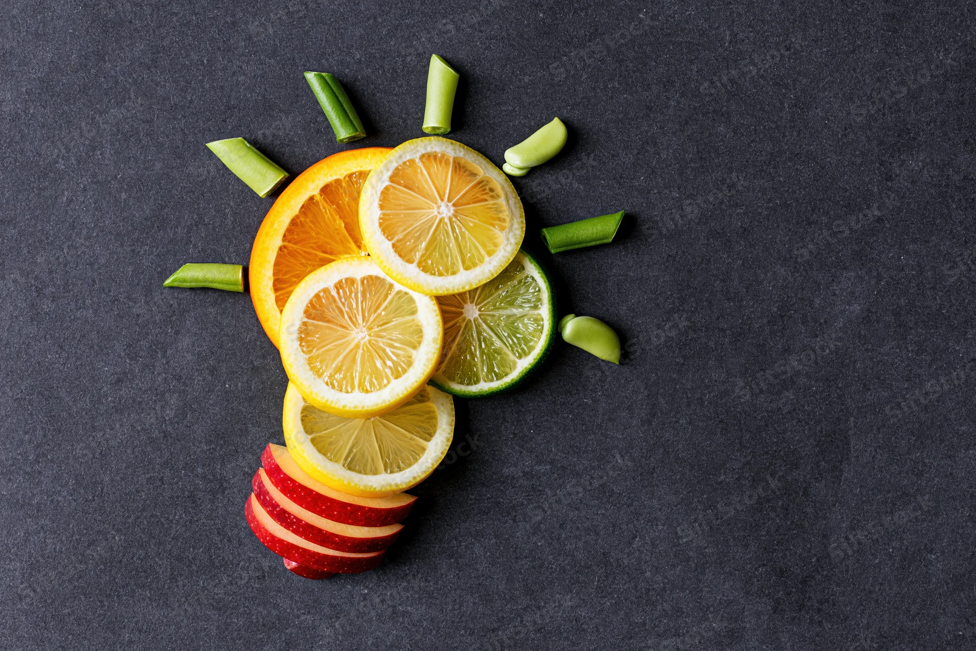 Citrus fruit slices arranged in lightbulb shape on dark surface
