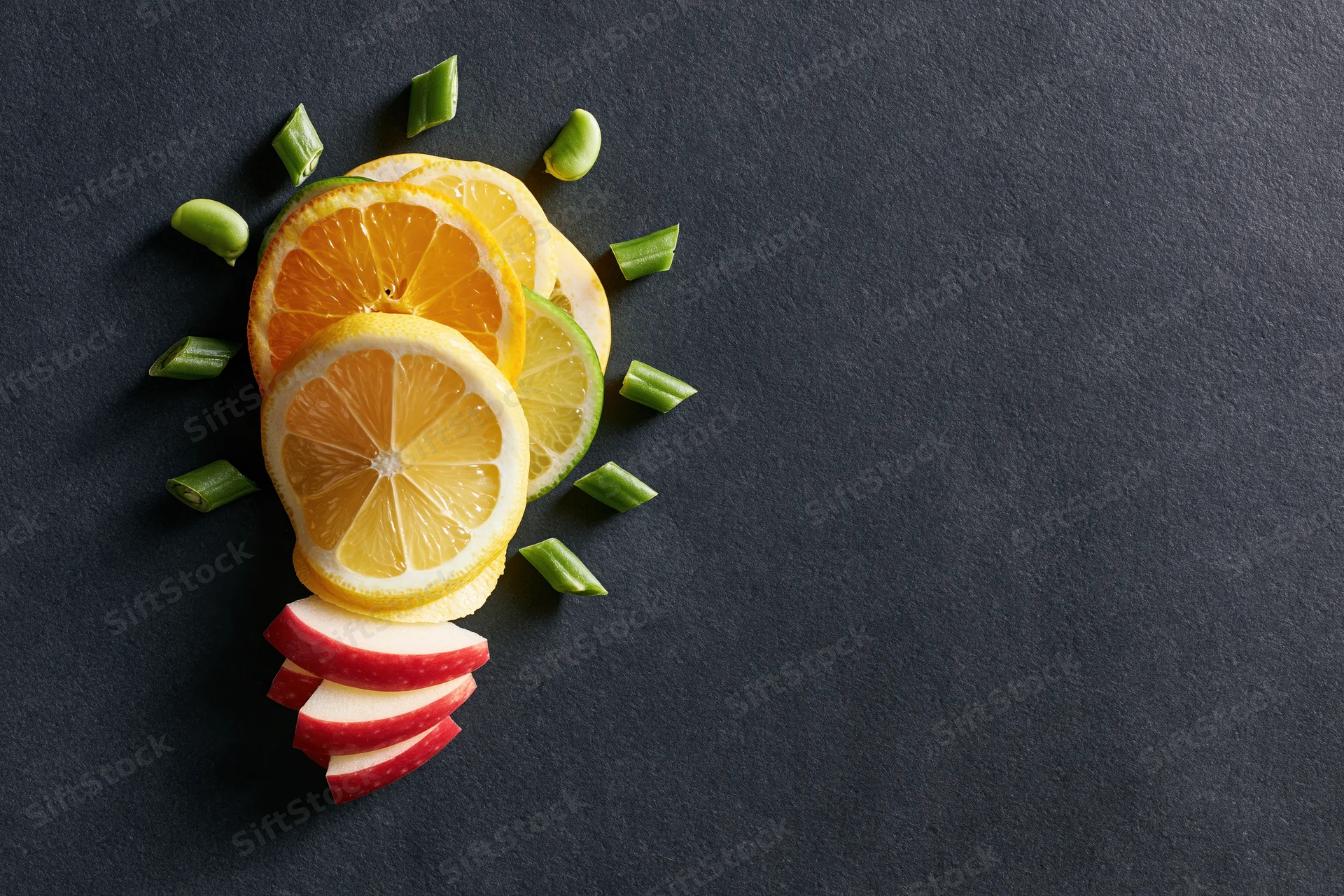 Citrus fruit slices arranged in lightbulb shape on dark surface with copyspace