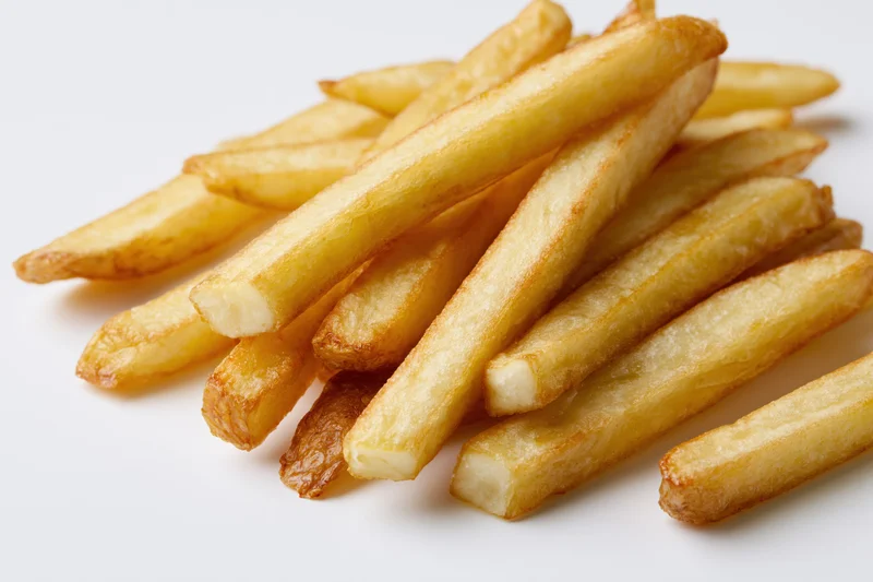 Golden french fries piled casually on a white surface