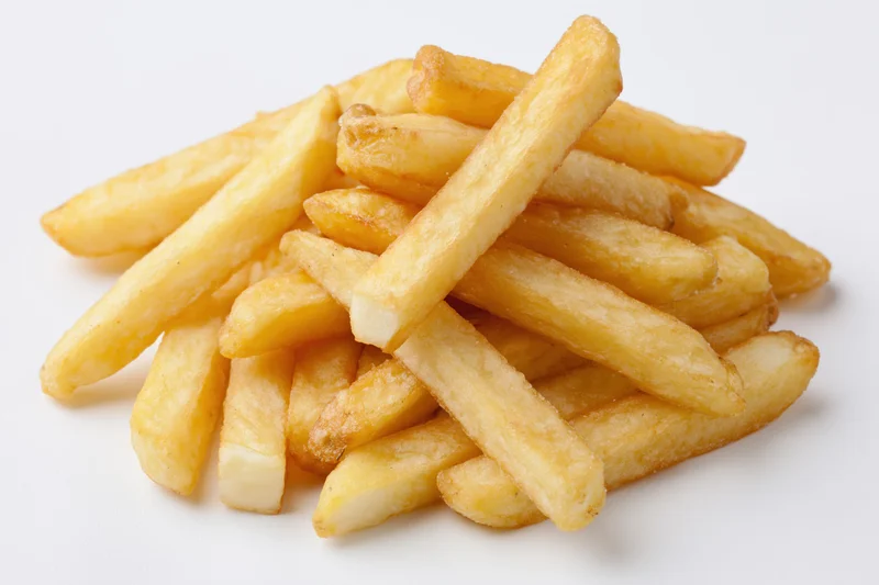 Pile of golden french fries stacked casually on white background