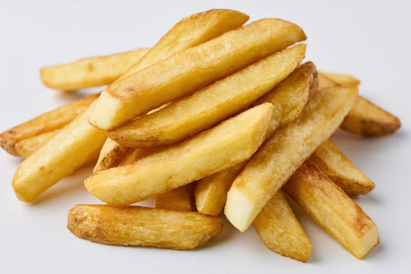 Golden french fries piled casually on a white surface