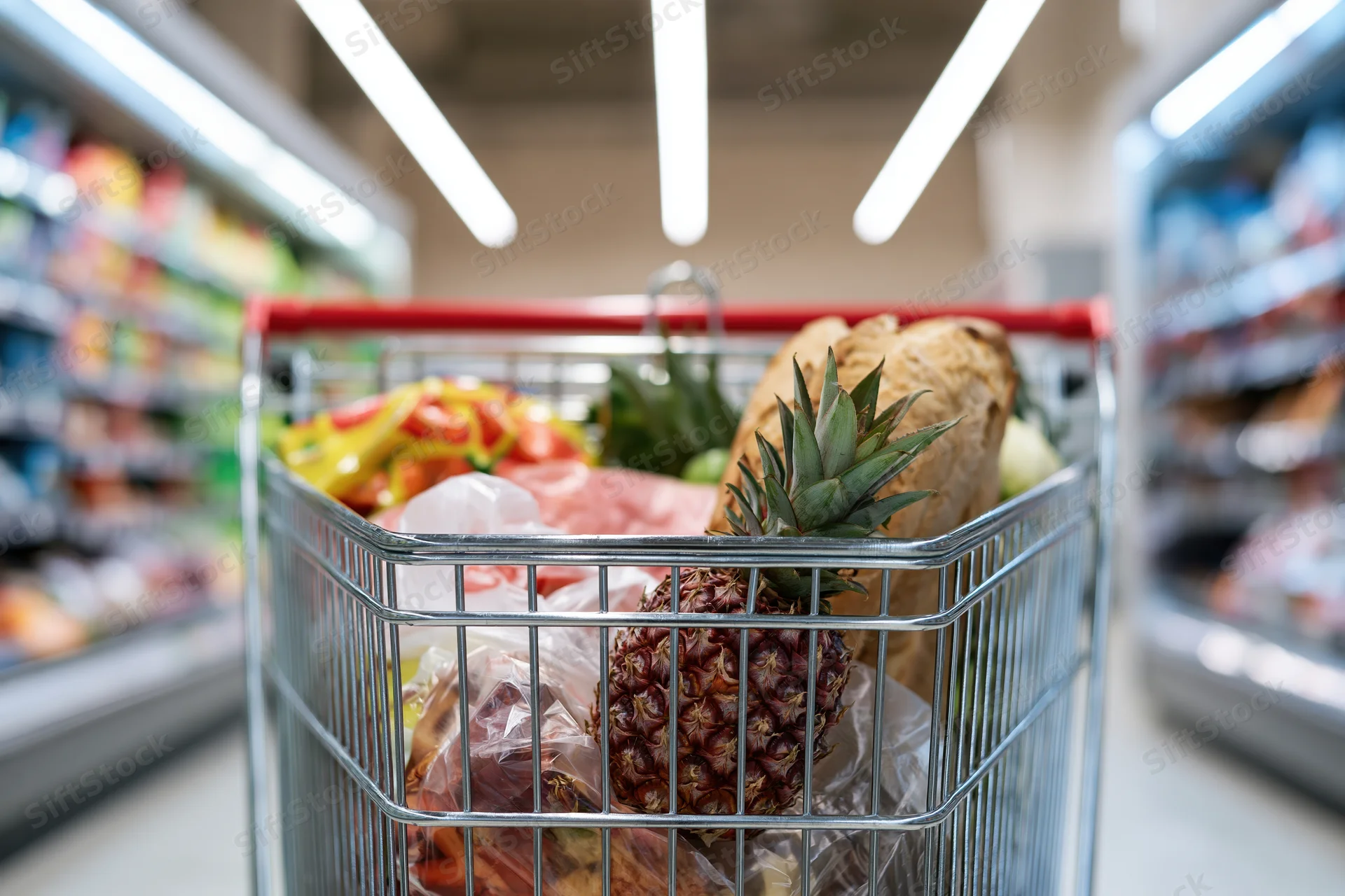 Metal shopping cart filled with groceries in a supermarket aisle