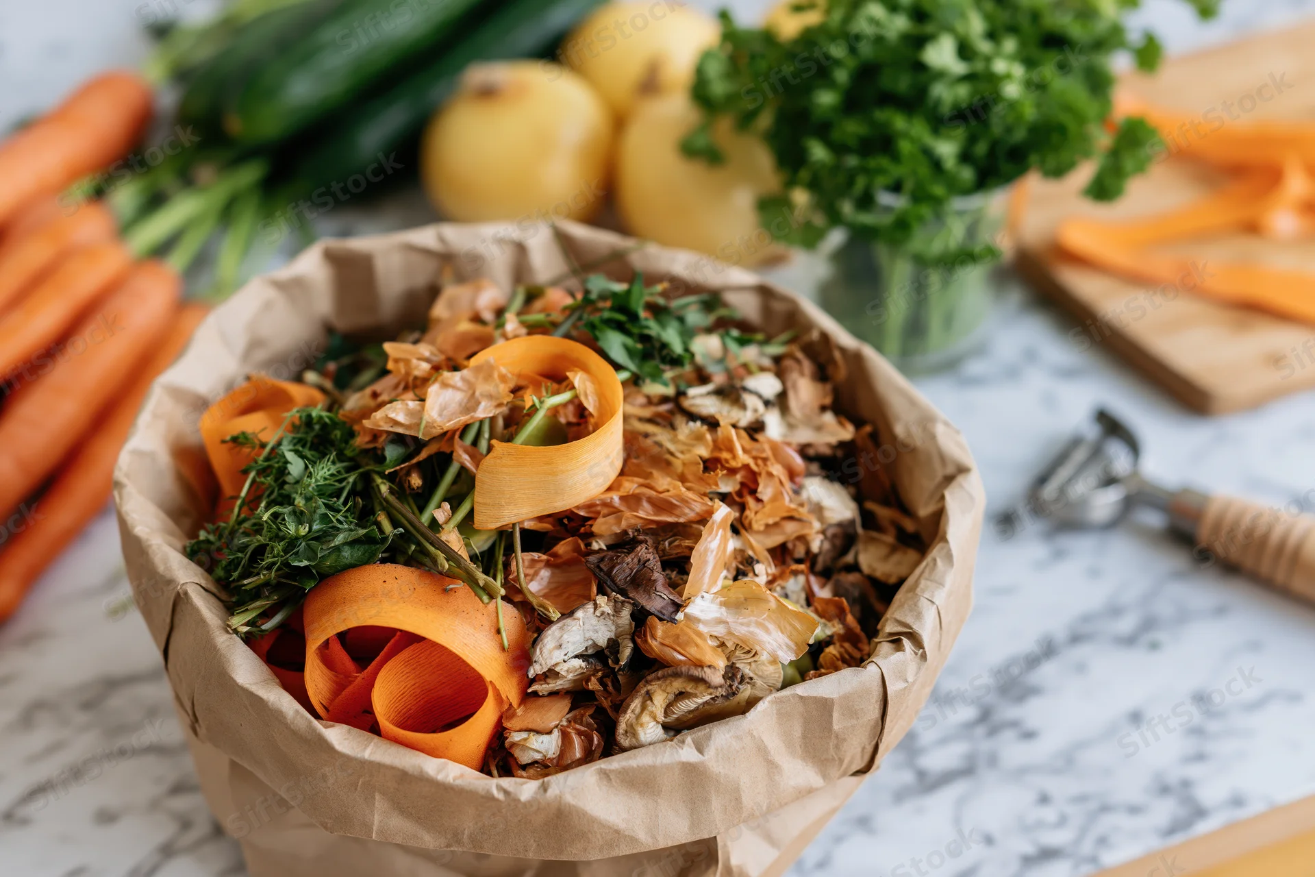 Paper bag filled with vegetable scraps and peels on a marble kitchen countertop
