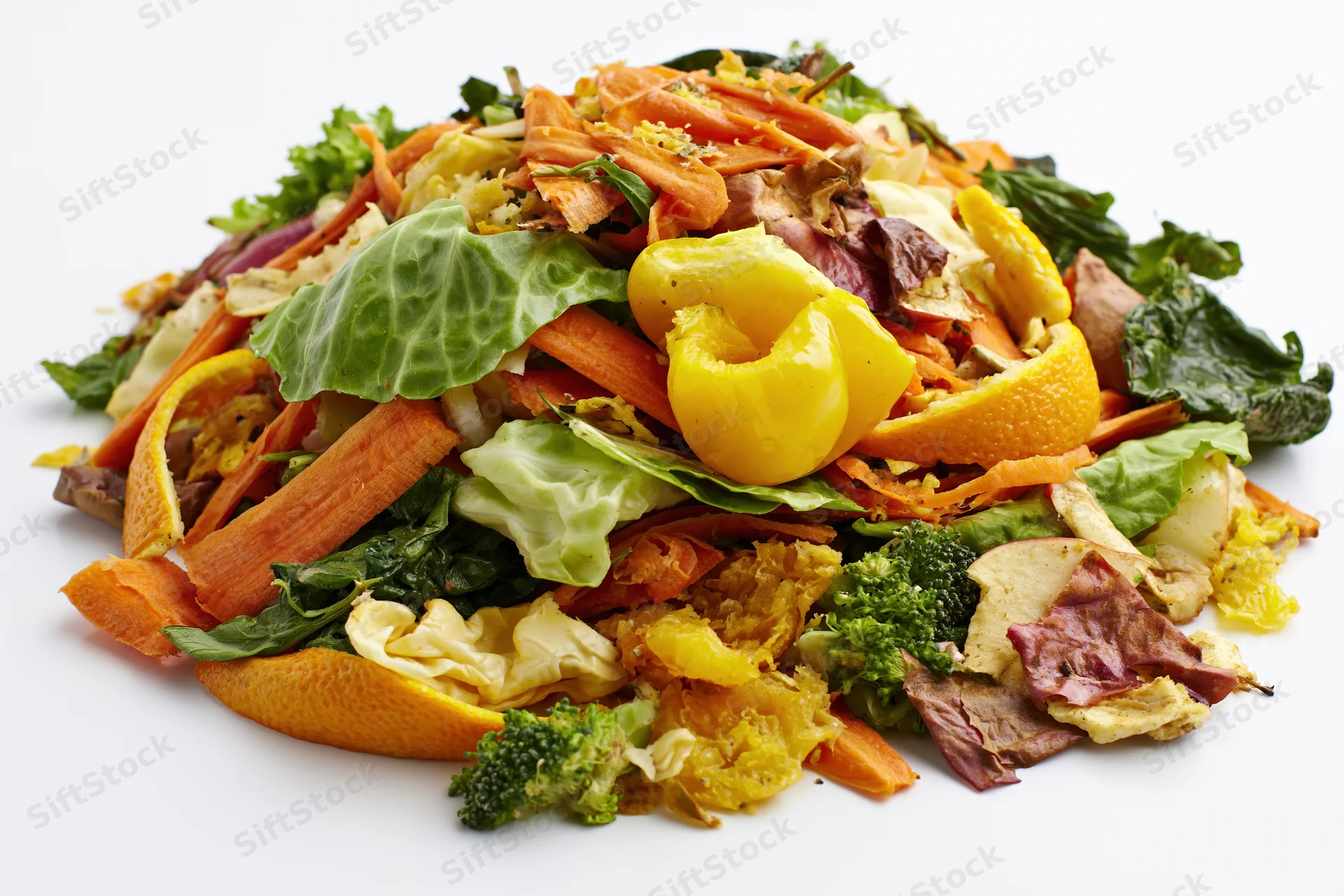 Pile of mixed vegetable and fruit kitchen scraps heaped on white background
