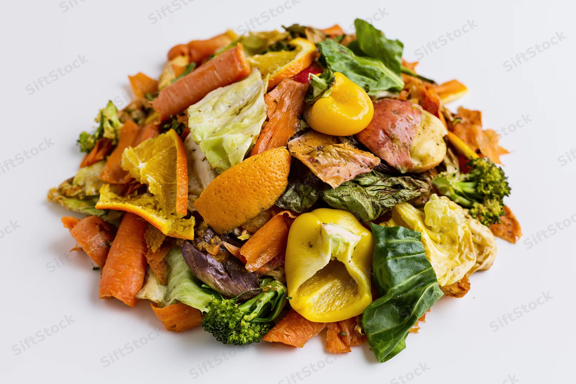 Pile of mixed vegetable and fruit kitchen scraps heaped on white surface