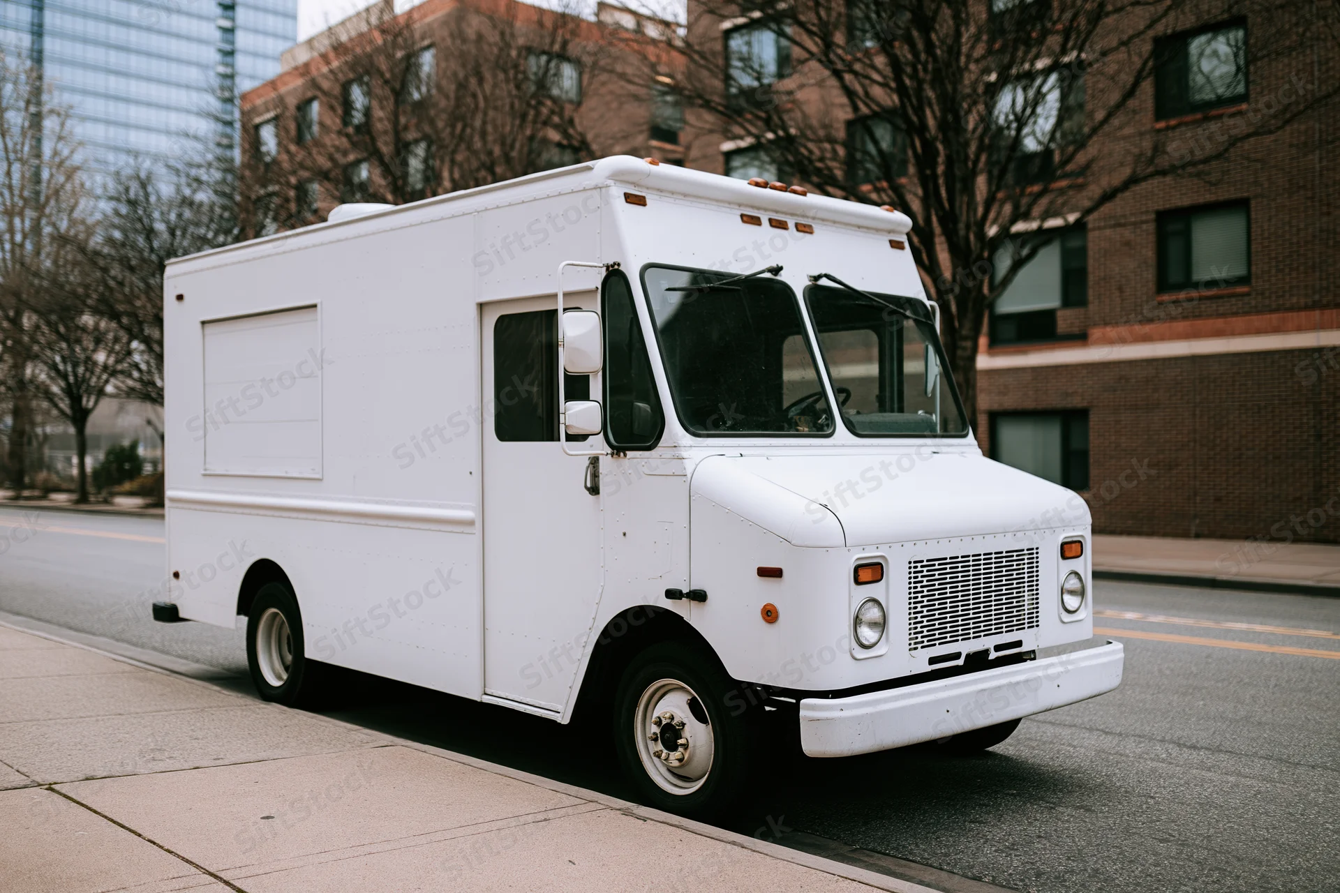White food truck parked along urban street sidewalk