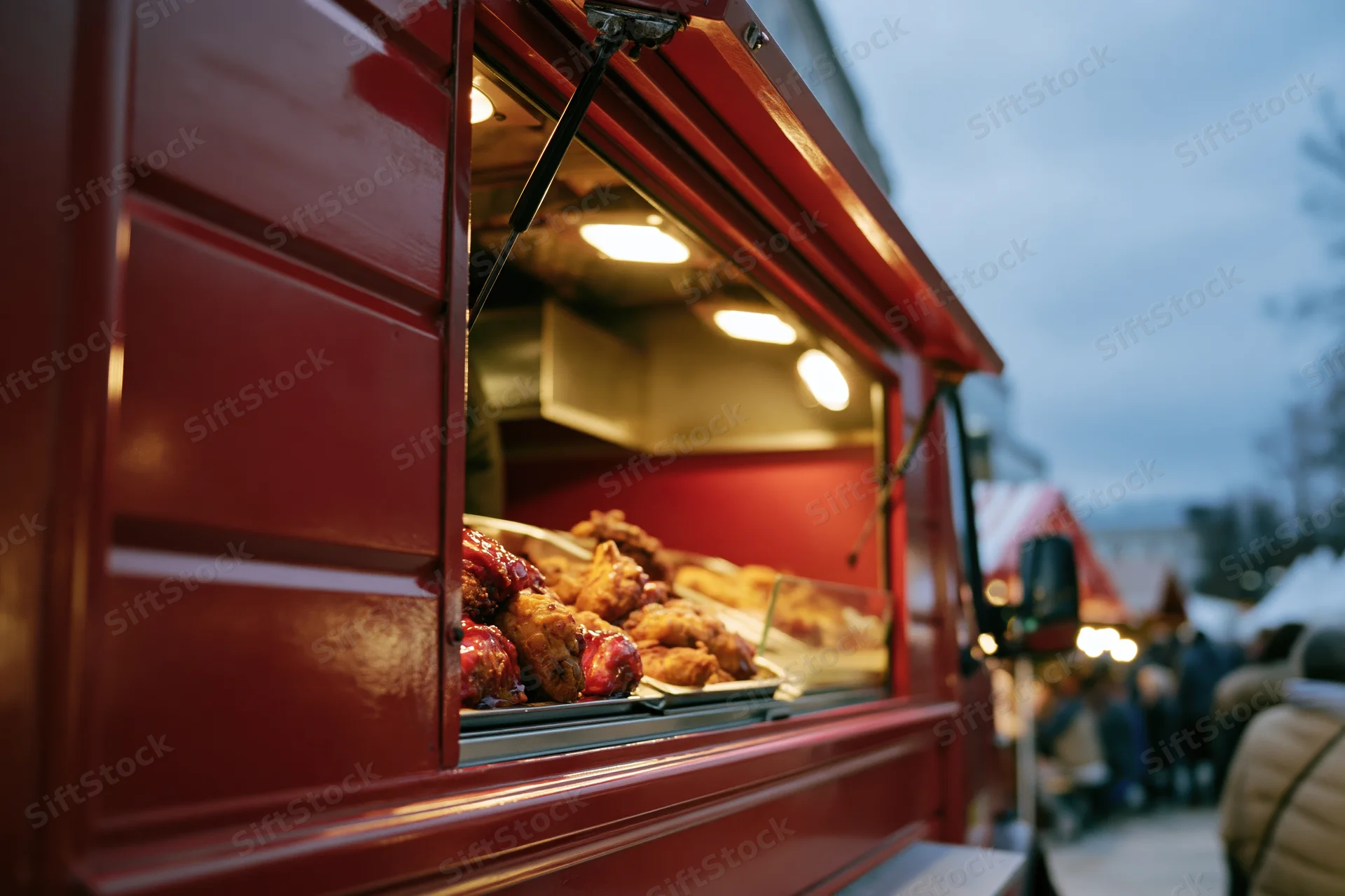 Red food truck with open service window displaying fried chicken and snacks at outdoor market