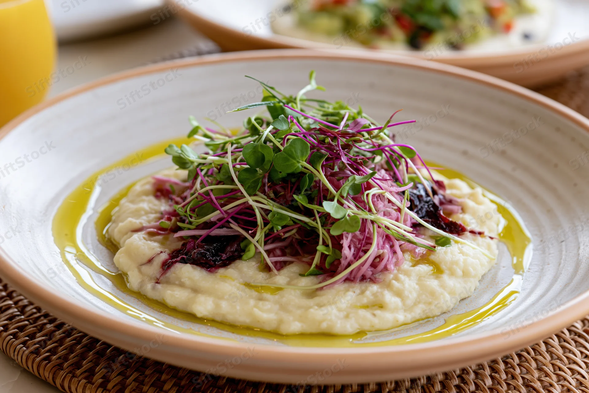 Mashed potato dish topped with microgreens and olive oil on a ceramic plate
