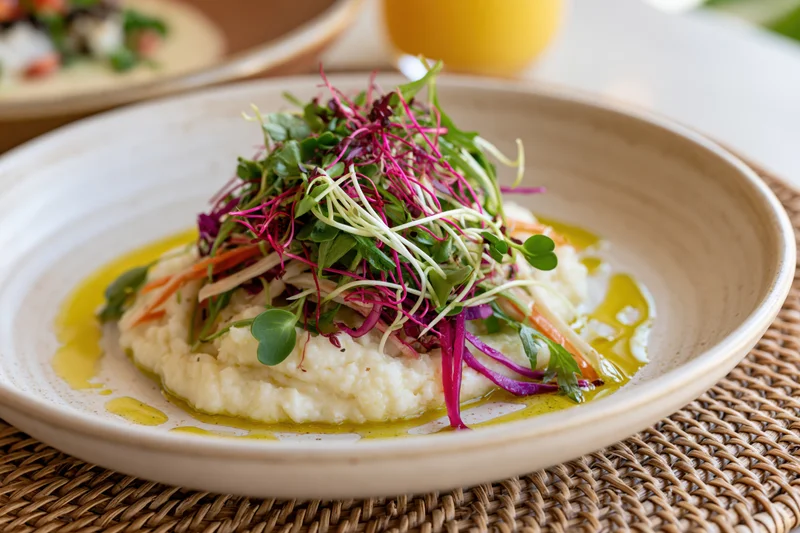 Mashed potato topped with colorful microgreens and olive oil on a ceramic plate