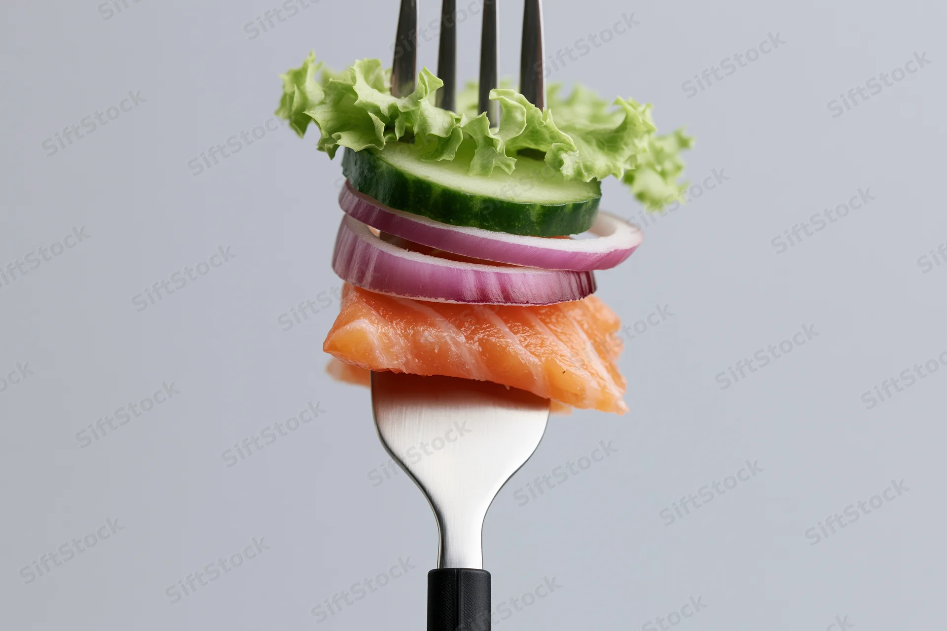 Fork holding stacked salmon, cucumber, red onion, and lettuce against a plain gray background