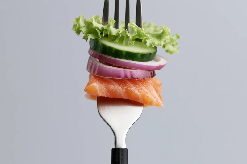 Fork holding stacked salmon, cucumber, red onion, and lettuce against a plain gray background