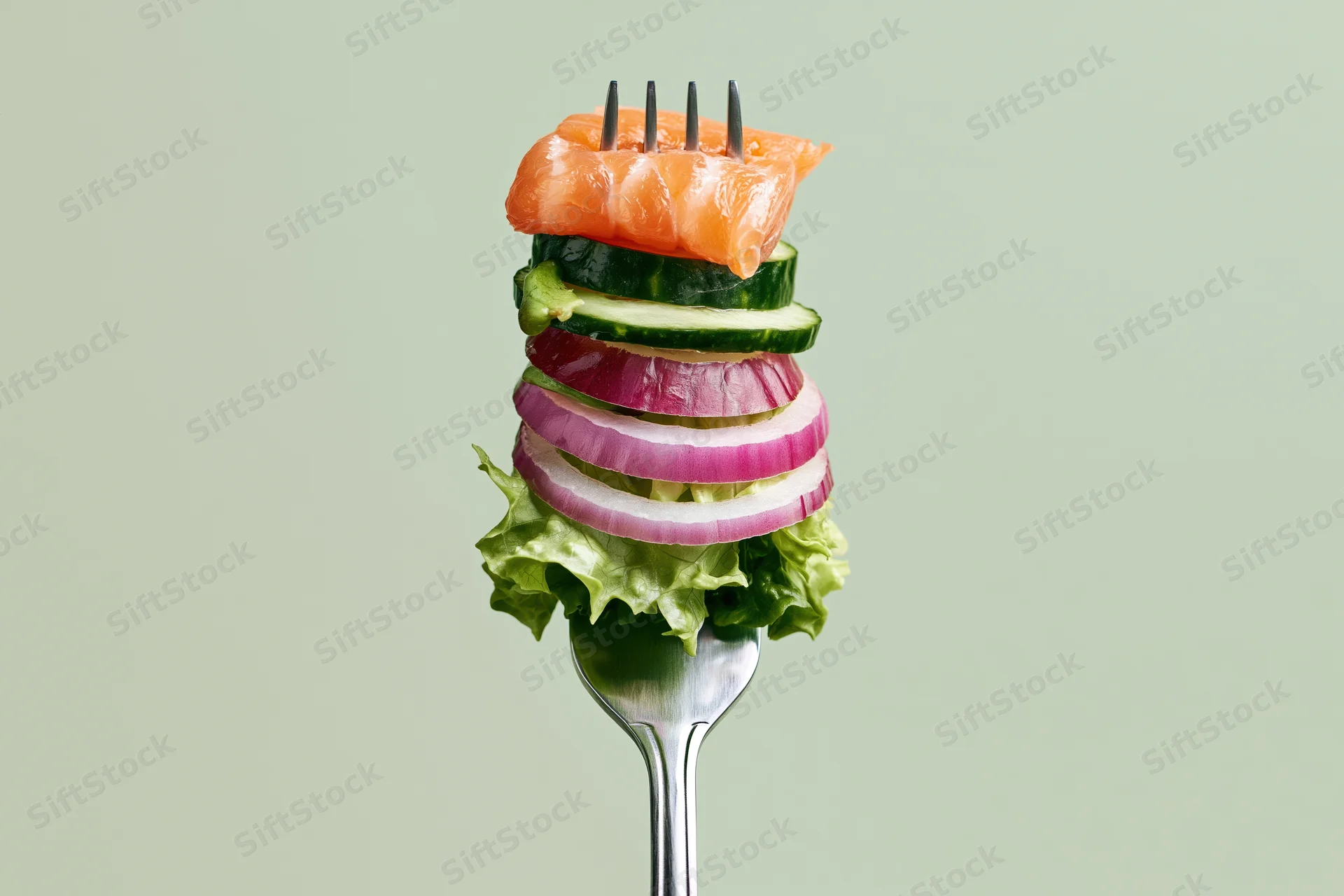 Fork holding stacked salmon, cucumber, red onion and lettuce against plain background