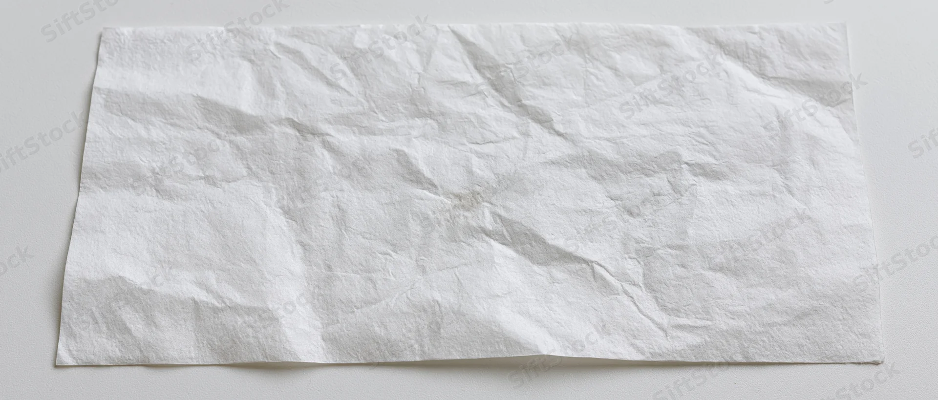 Crumpled white paper sheet lying flat on a neutral surface