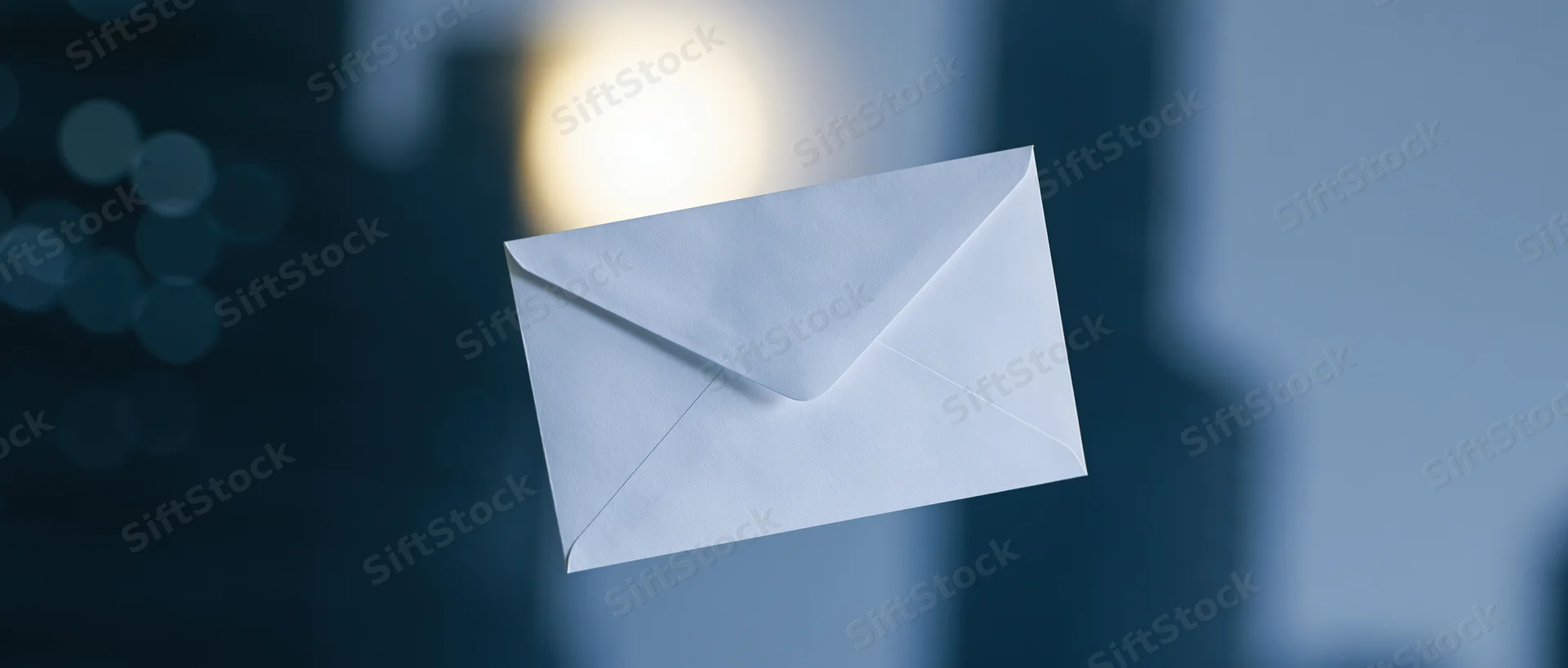 White paper envelope floating in front of blurred city lights at night
