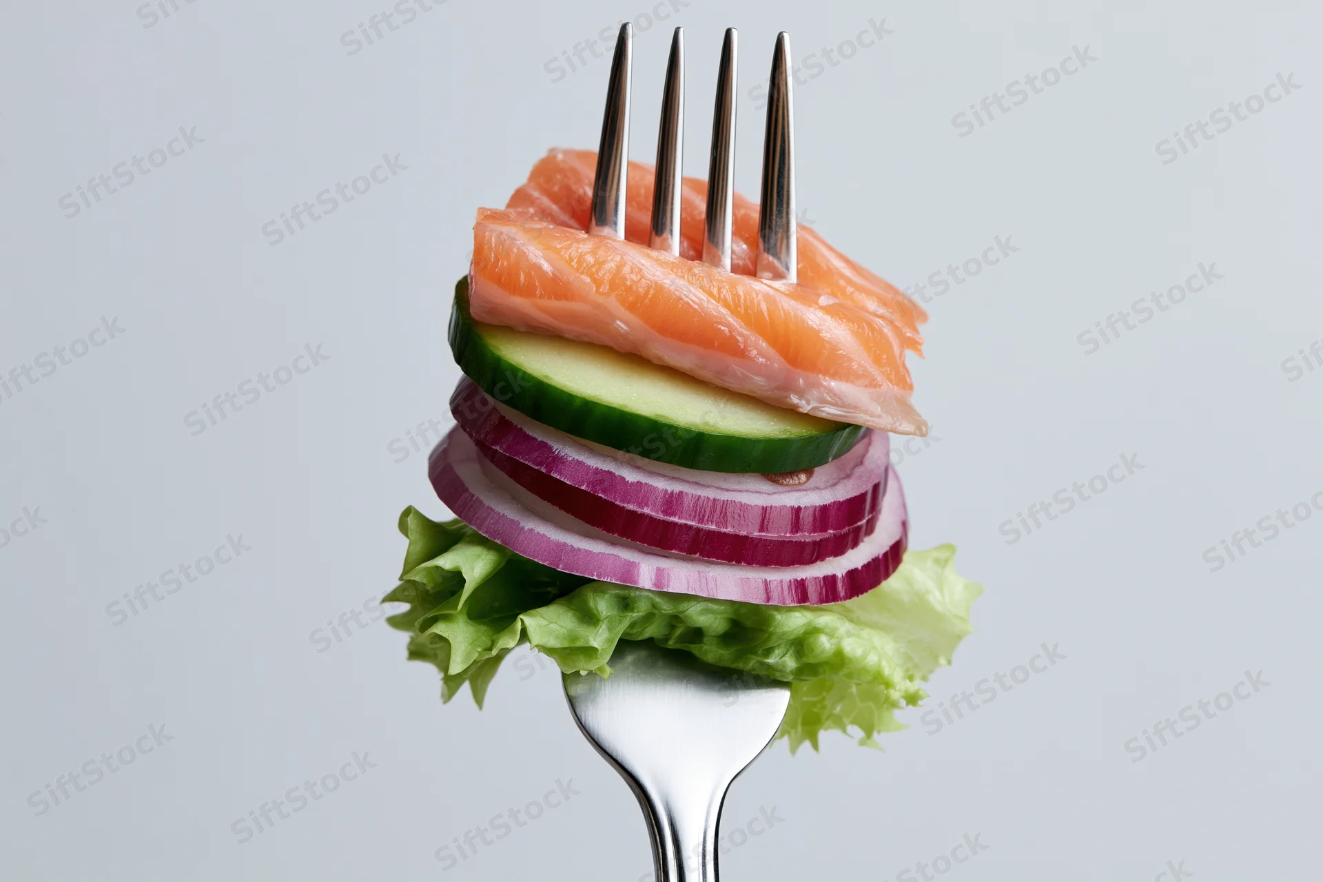Fork holding stacked salmon, cucumber, red onion, and lettuce against white background