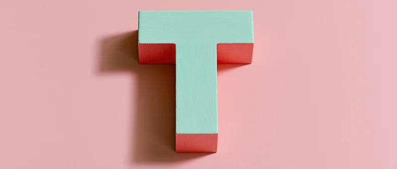 Wooden letter t mounted flat against a pink background with soft shadow